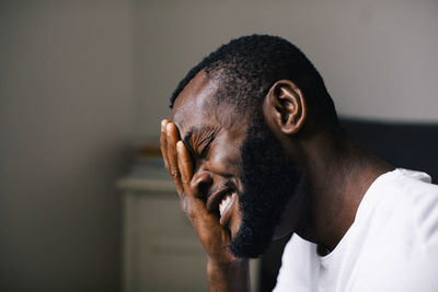 Smiling bearded man hand on with closed eyes at home