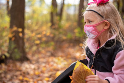 Cute girl wearing mask sitting at park