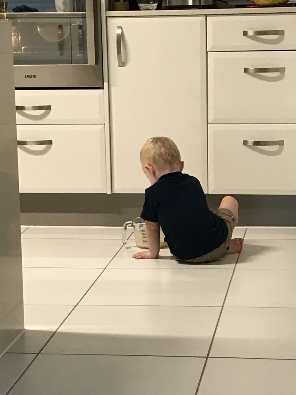 REAR VIEW OF BOY SITTING ON FLOORING