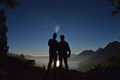 Silhouette male friends standing against sky