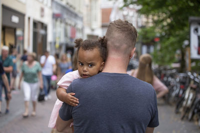 A father carrying his young daughter through streets of europe