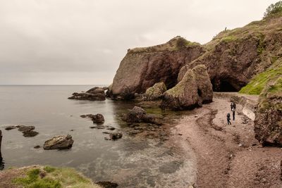 Rock formations by sea against sky