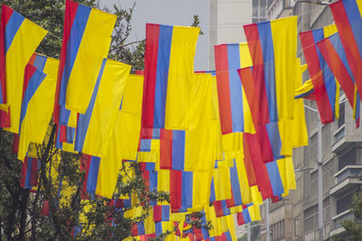Low angle view of colorful flags hanging against buildings