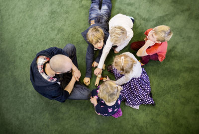 Directly above shot of teacher with students playing on rug in kindergarten