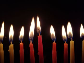 Close-up of burning candles against black background