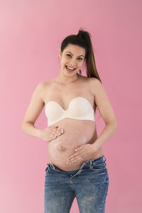 Portrait of a smiling young woman against pink background