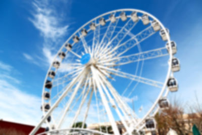 Low angle view of ferris wheel against cloudy sky