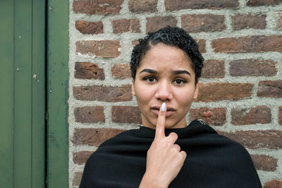 Portrait of woman standing against brick wall