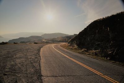 Road leading towards mountain against sky