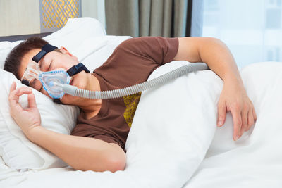 Man wearing oxygen mask while sleeping on bed at hospital