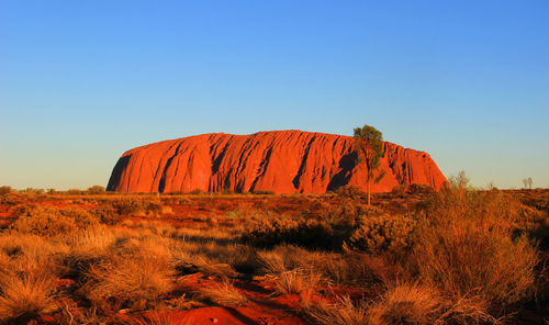 Rock formations on landscape against clear blue sky