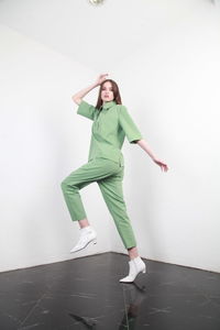 Full length portrait of teenage girl standing against wall