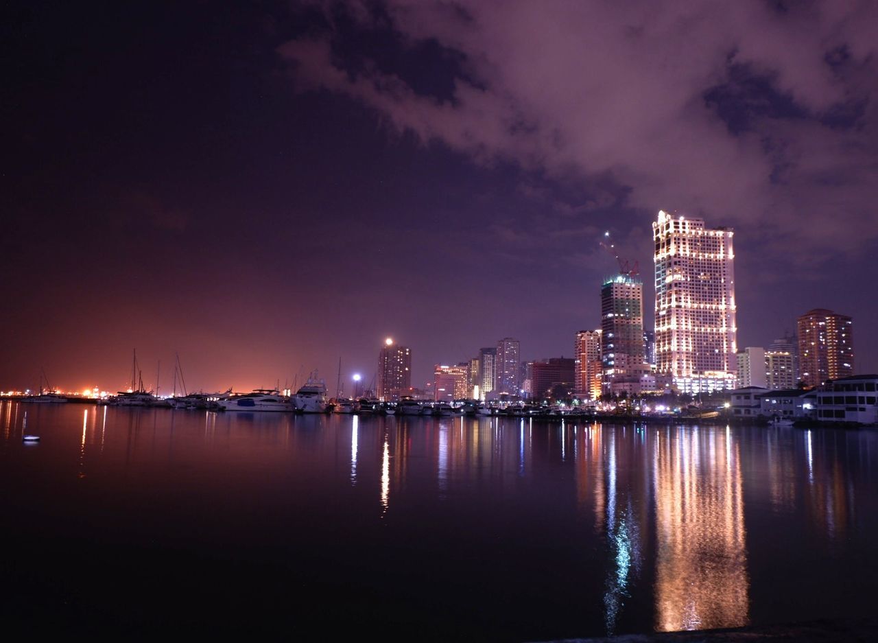 night, illuminated, city, water, architecture, sky, building exterior, reflection, built structure, building, urban skyline, cloud - sky, landscape, waterfront, city life, nature, no people, office building exterior, cityscape, skyscraper