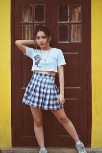 Portrait of teenage girl standing against yellow door