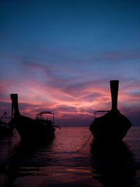 Silhouette boat moored in sea against sky during sunset