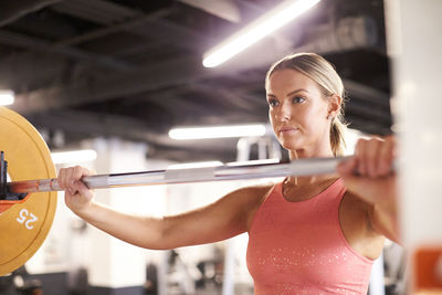 A portrait of a blonde woman lifting weights in the gym.
