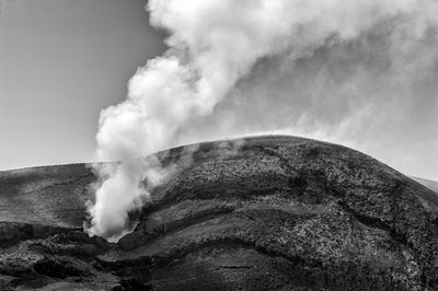 Smoke emitting from volcanic mountain against sky