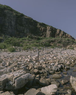 Stone wall by rocks against clear sky