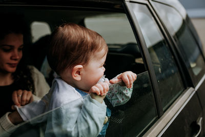 High angle view of boy looking through car window