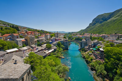 High angle view of townscape by sea against clear blue sky