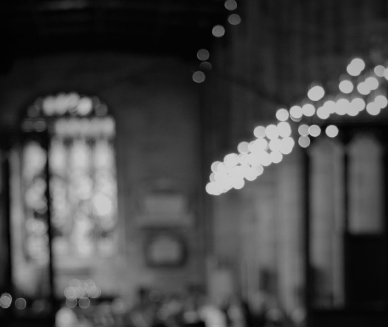 DEFOCUSED IMAGE OF ILLUMINATED LIGHTING EQUIPMENT HANGING AT BUILDING