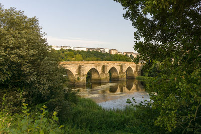 Arch bridge over river against clear sky