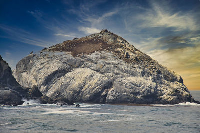 Scenic view of sea and rocky mountain against sky