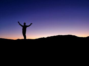 Silhouette man standing on mountain against sky during sunset