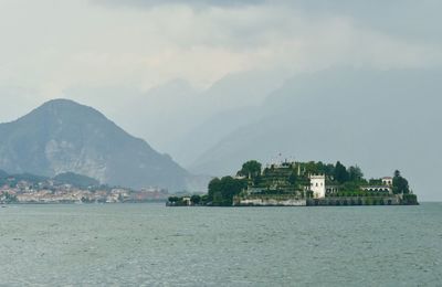 Scenic view of sea by townscape against sky