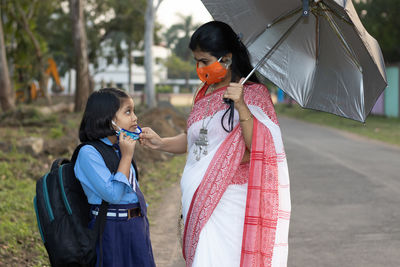 An indian school girl child going to school again after pandemic with her mother