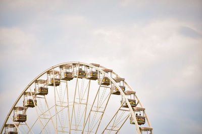 Low angle view of ferris wheel against cloudy sky