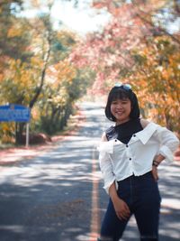 Portrait of smiling woman standing on road