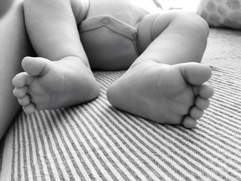 Low section of baby lying on bed