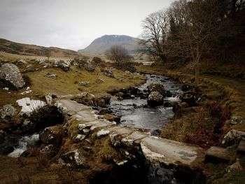 Scenic view of river by mountains against sky