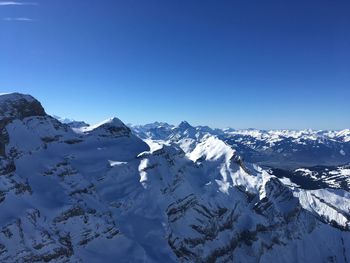 Scenic view of snowcapped mountains against clear blue sky