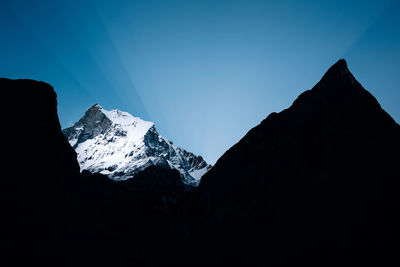 Silhouette mountains against clear blue sky during winter