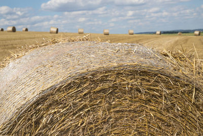 Close-up of hay bales on field against sky