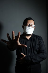 Portrait of young man standing against gray background