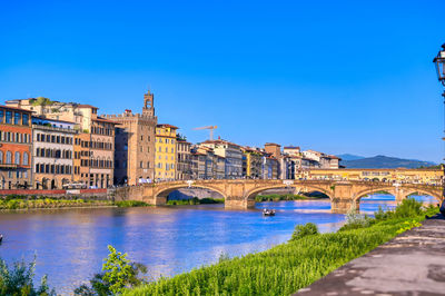 Arch bridge over river against blue sky