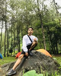 Young man sitting on rock in forest