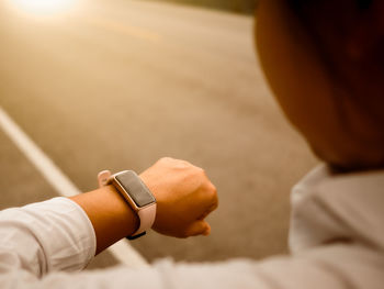 Close-up of hand holding clock against blurred background