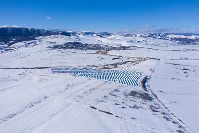 Aerial drone view of snow covered solar panel park, photovoltaic power station in the winter