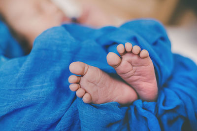 Low section of baby sleeping on bed