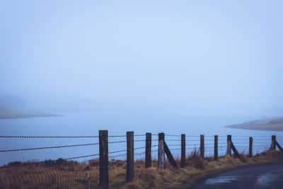 Fence on beach against clear sky