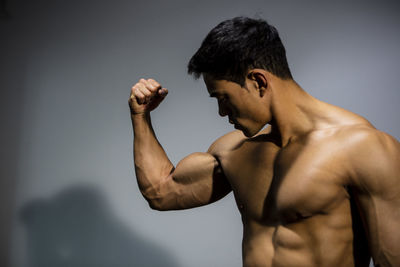 Shirtless muscular man standing against wall