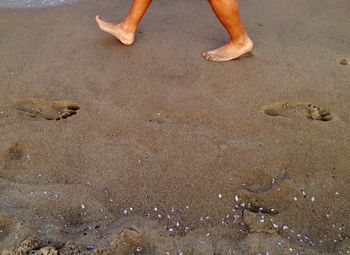 Low section of person walking at sandy beach