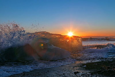 Sea waves splashing on shore during sunset