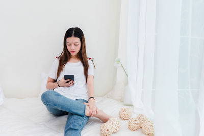 Young woman using mobile phone while sitting at home