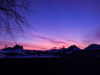 Scenic view of silhouette houses and trees against sky at sunset