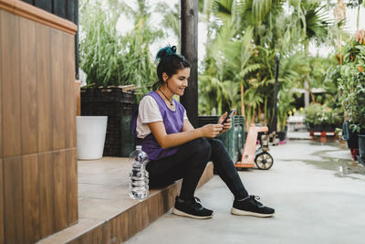 Female owner using smart phone while sitting in nursery